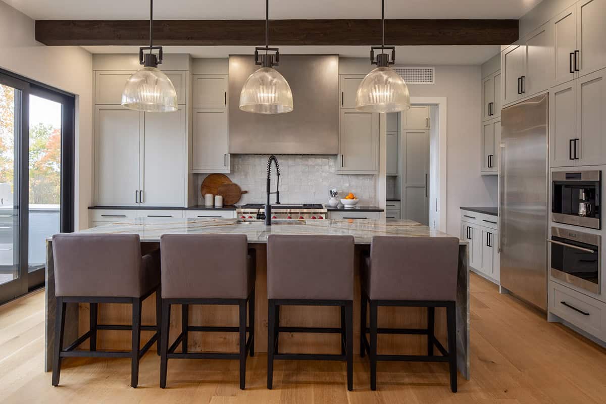 Kitchen island seating beneath three glass ribbed pendant lights
