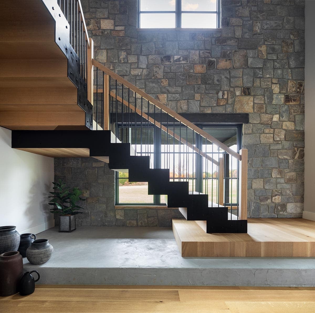 Floating wood and steel stairway against a stone accent wall