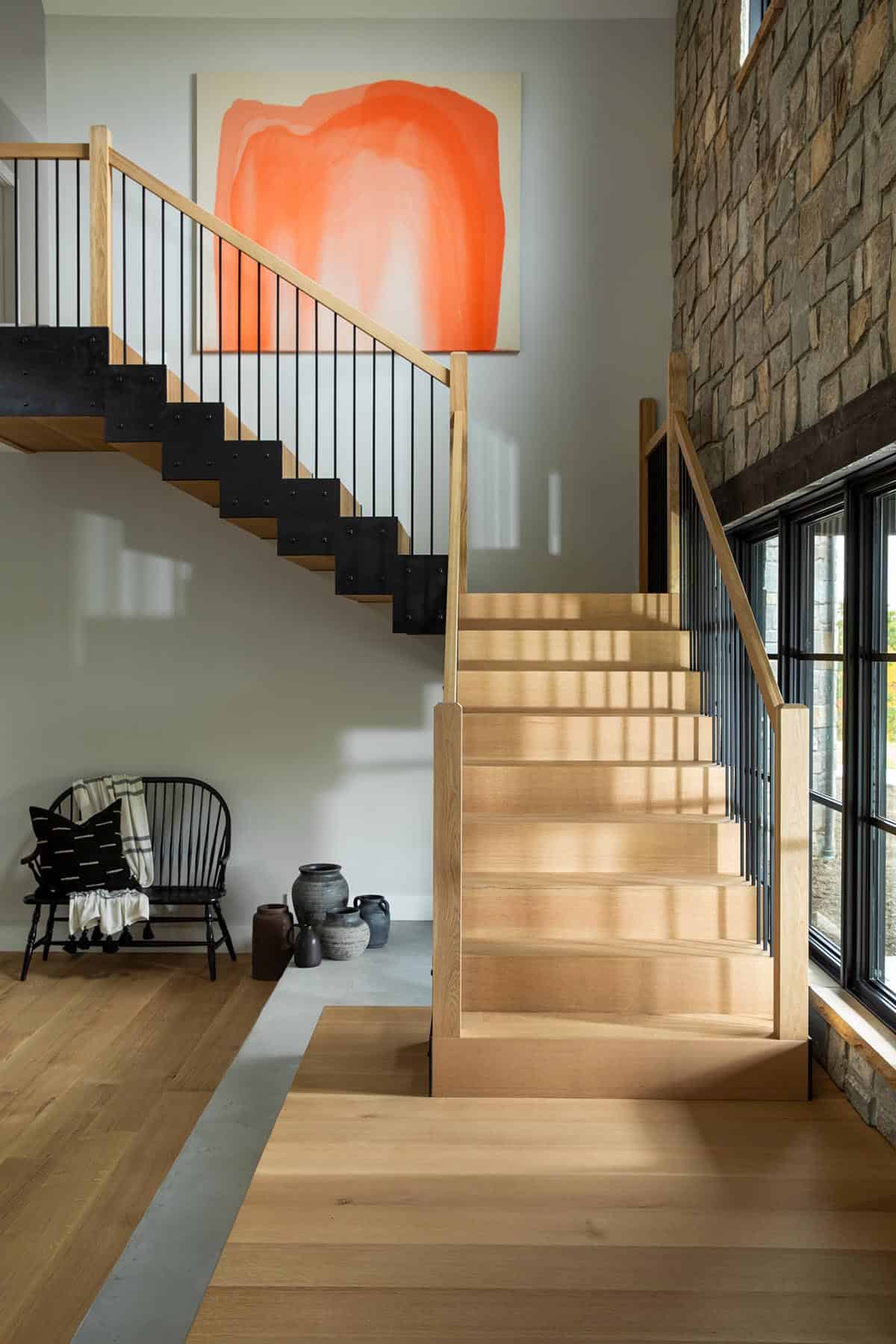 Wood staircase with black steel treads beneath an orange painting