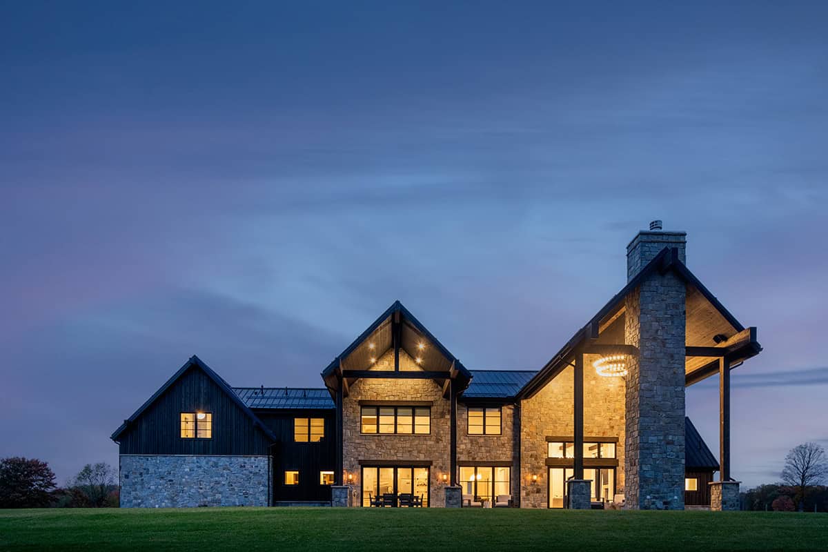 Rear exterior at dusk with dark timber and stone gables