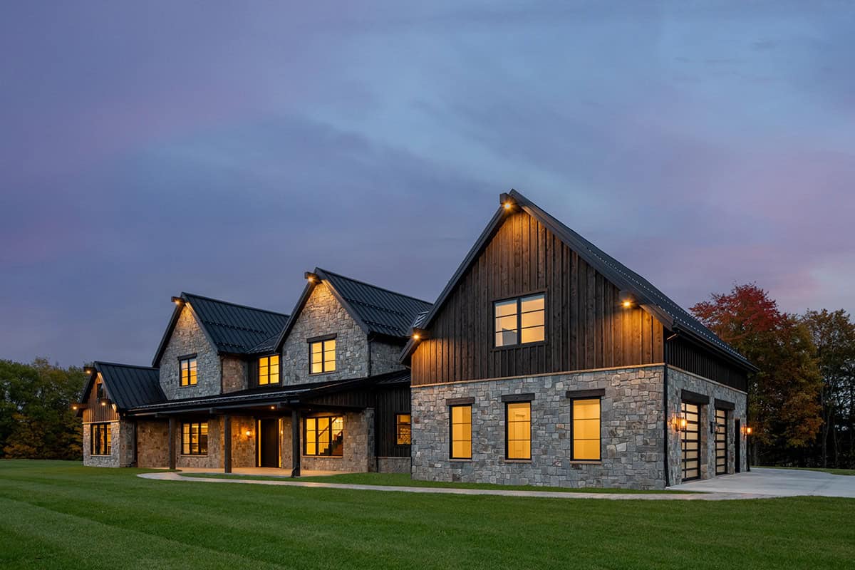 Side exterior at dusk showing stone and dark wood siding