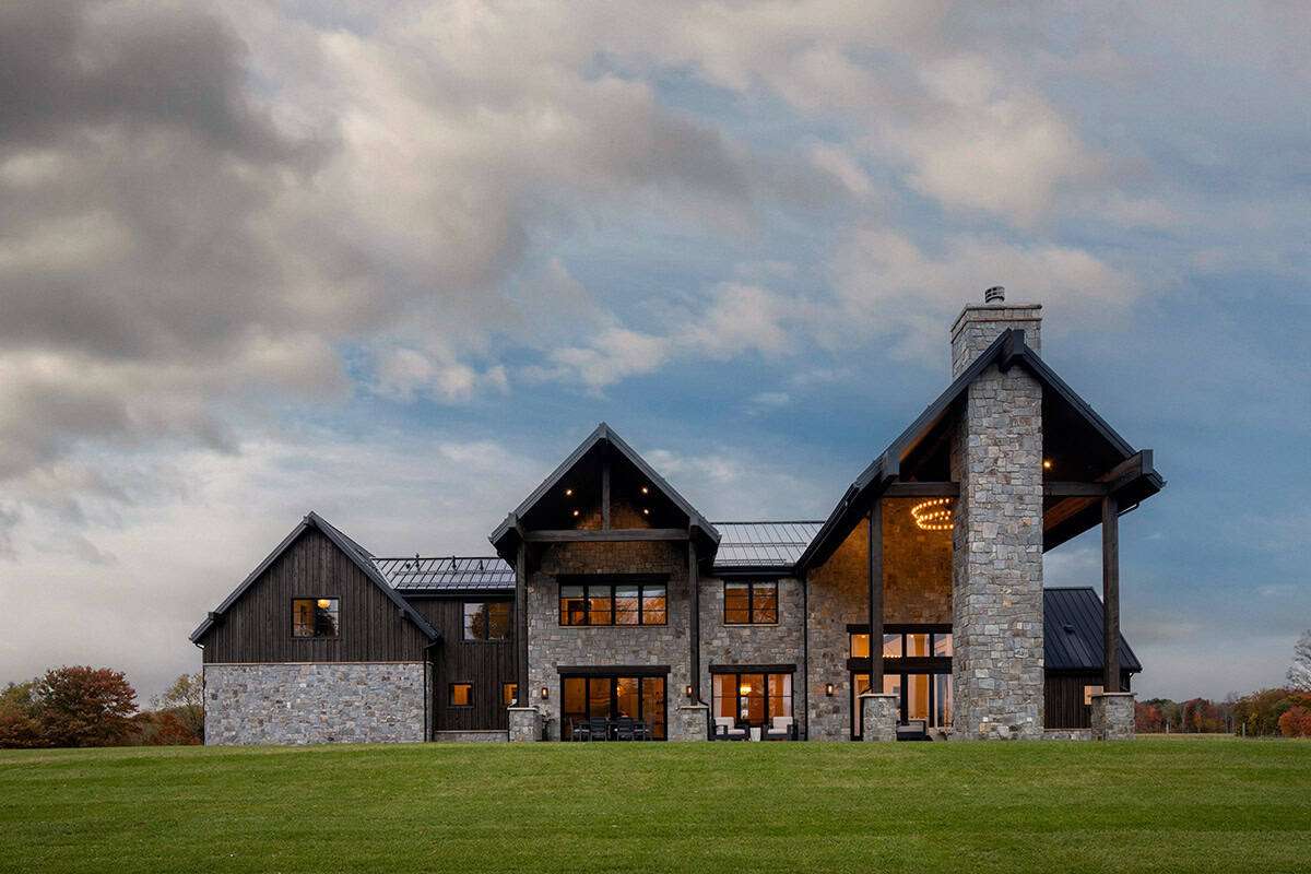Rear exterior at dusk with glass doors and stone chimney