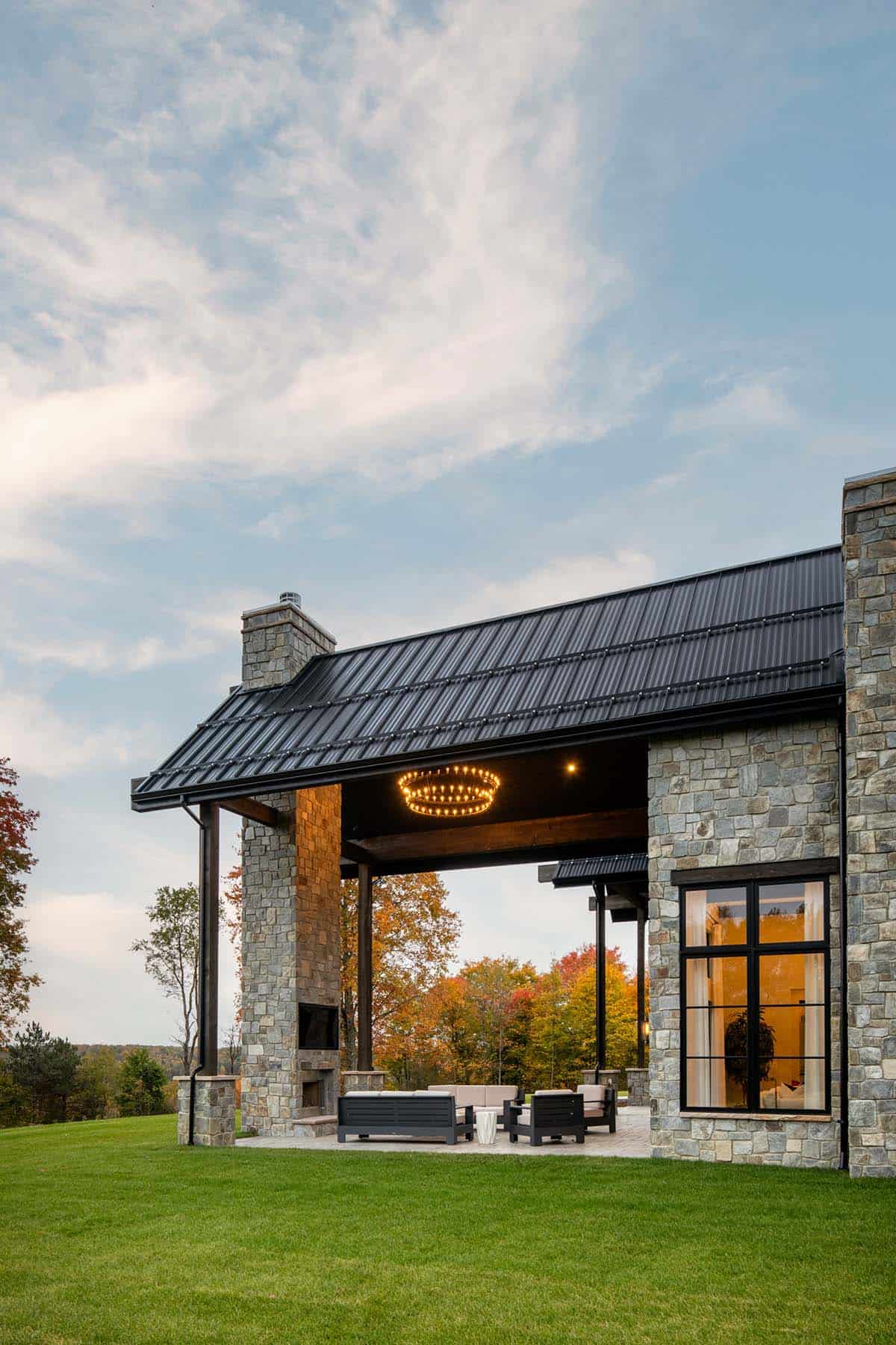 Covered outdoor living area with stone fireplace and fall foliage