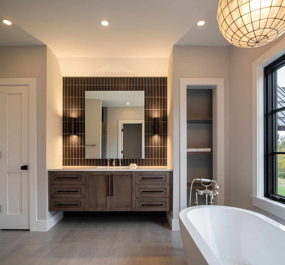 Primary bathroom vanity with dark tile backsplash and globe pendant