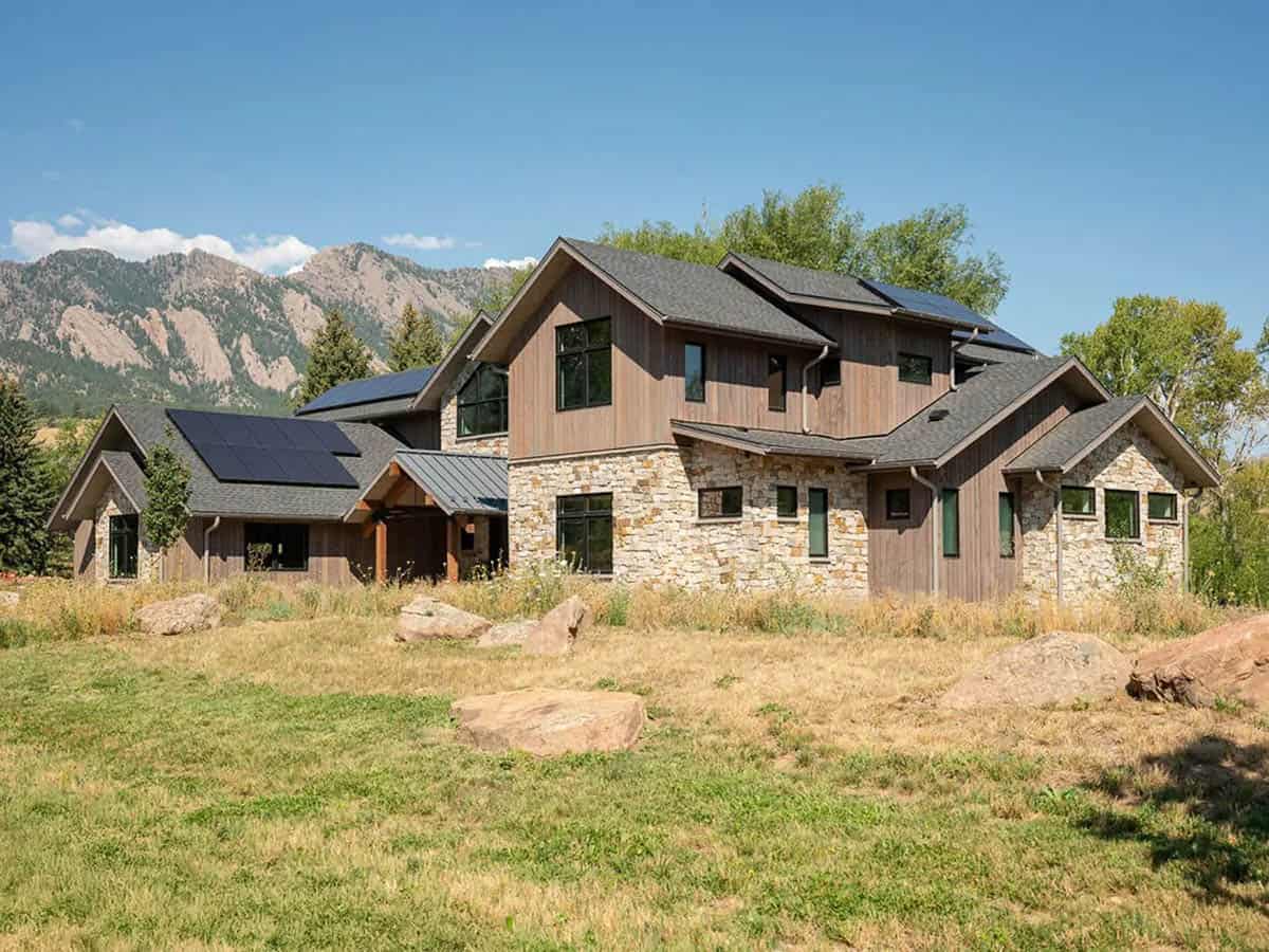 Side exterior with stone, vertical wood siding, and solar panels