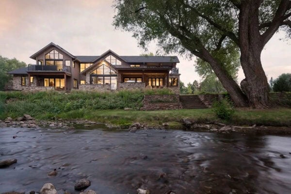 Creekside rear elevation with tall glass gables and a large tree