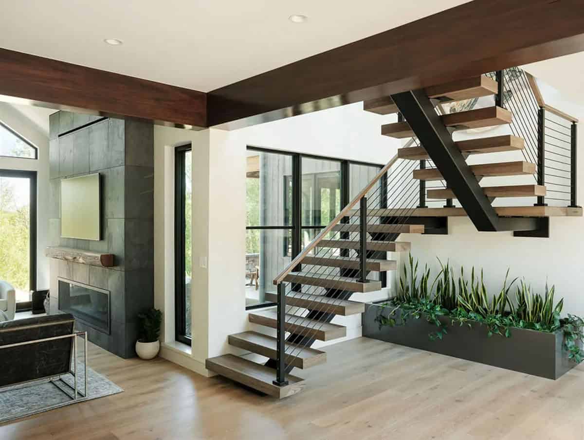 Open floating staircase with cable railing, slate fireplace, and indoor planter