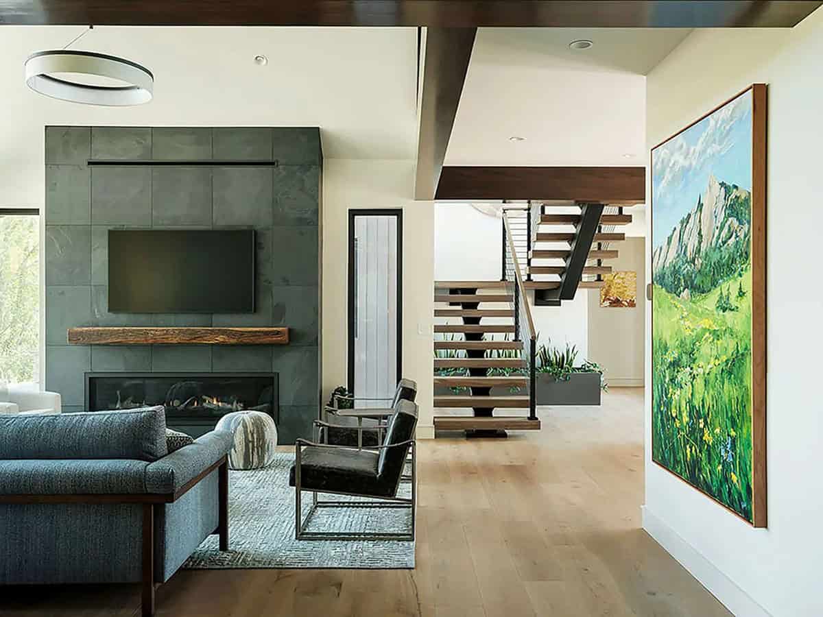 Living room with slate fireplace, blue sofa, and mountain landscape painting