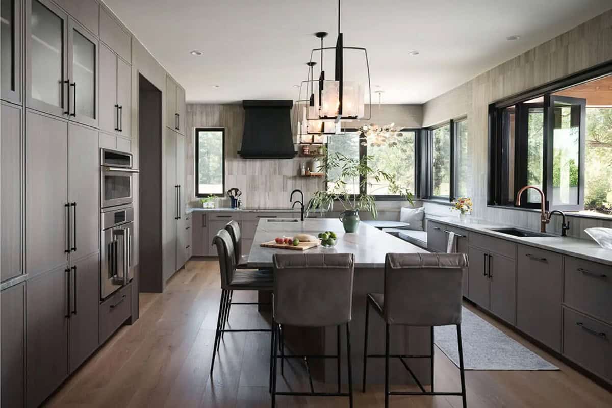 Kitchen with large island, black range hood, and muted gray cabinetry