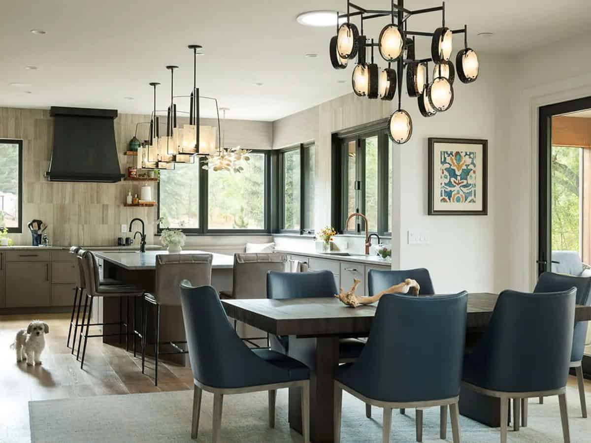 Open kitchen and dining area with sculptural chandelier and navy leather chairs