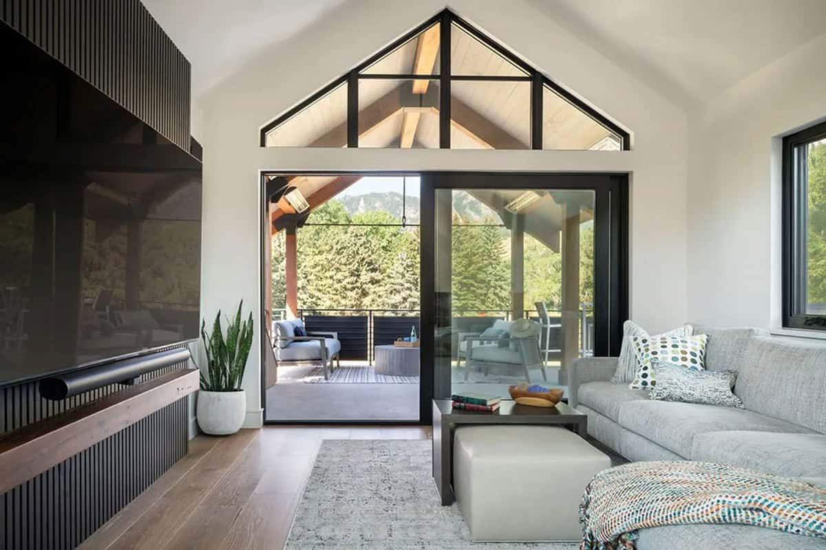 Loft sitting area with gray sectional, slat media wall, and covered deck