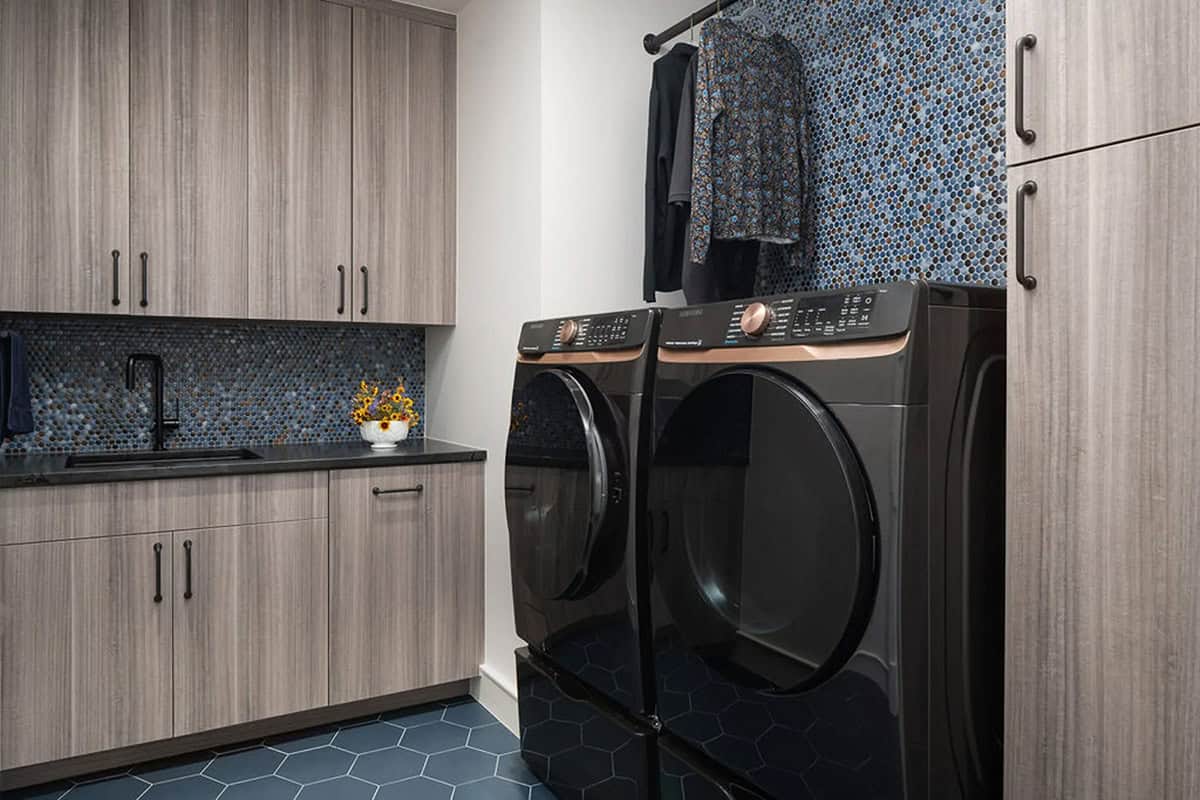 Laundry room with black washer and dryer and blue penny tile backsplash