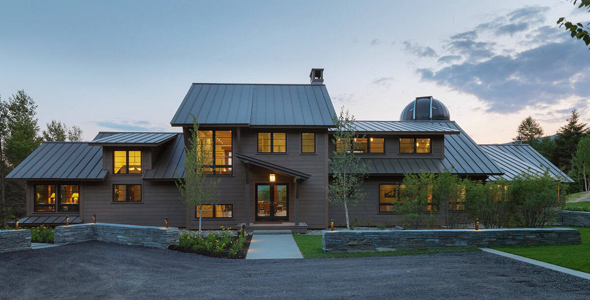 Front entrance at dusk with gravel driveway and stone retaining walls