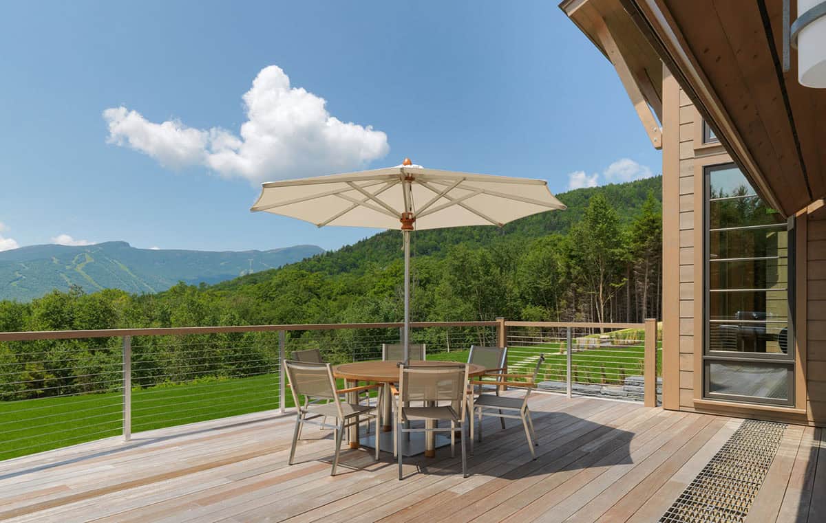 Deck dining table with umbrella overlooking forested mountain ridge