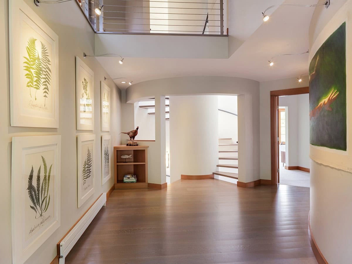 Curved hallway gallery wall with botanical prints and staircase view