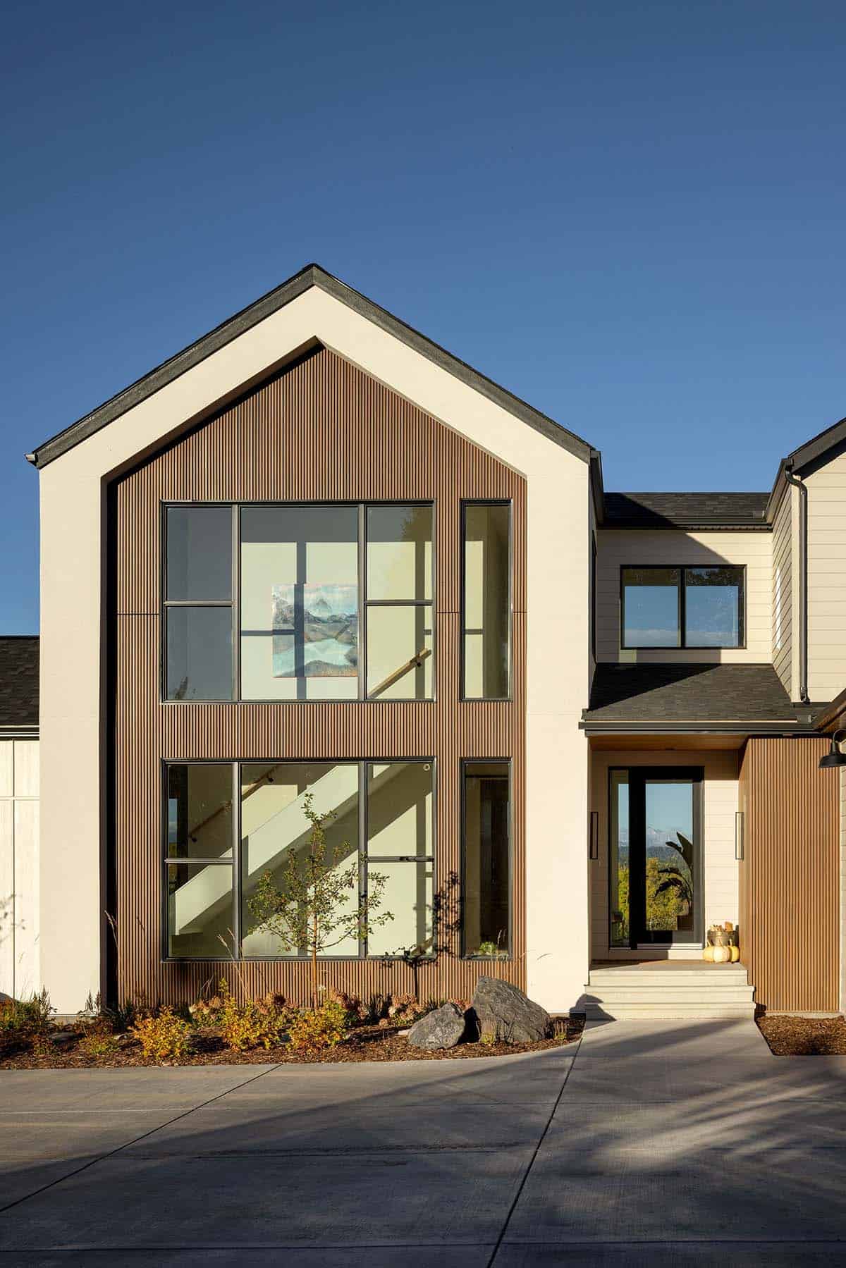 Close-up of gabled entry with vertical wood siding and glass staircase window