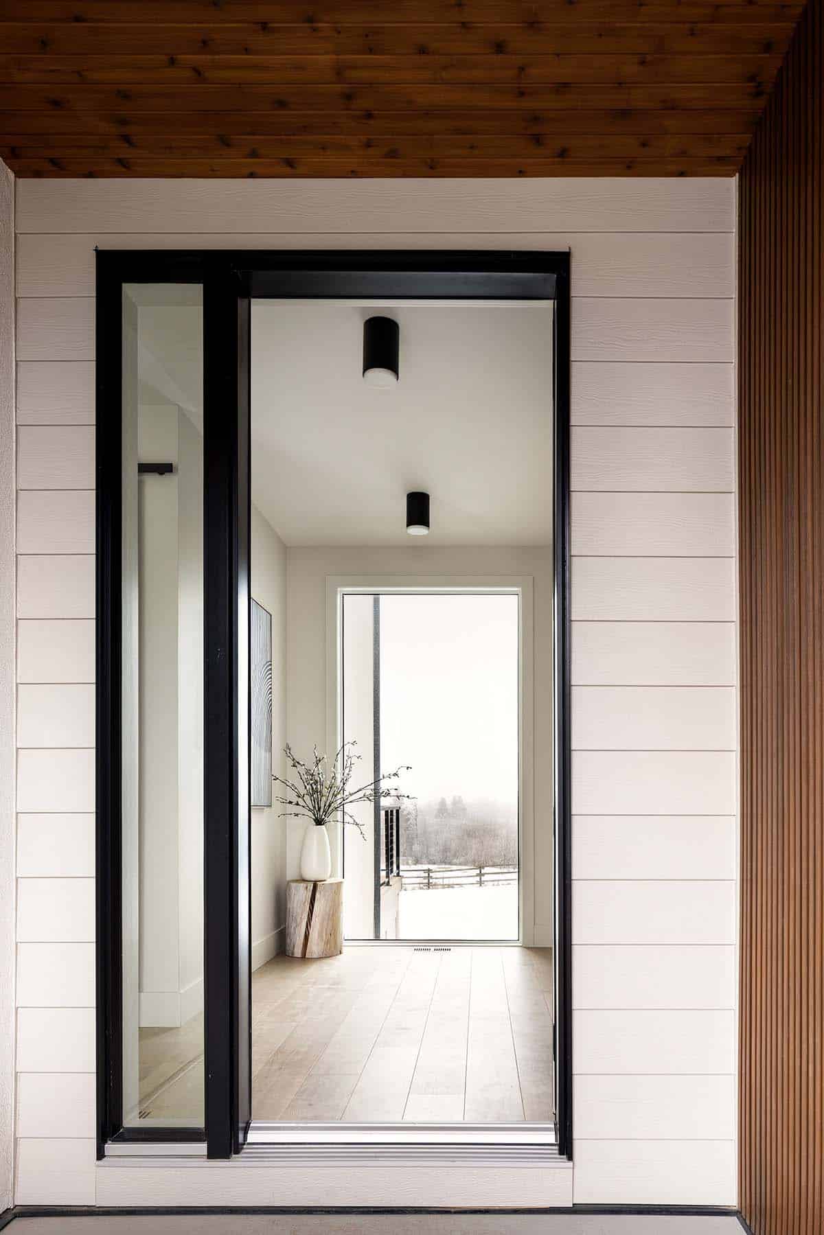Front entry door with wood ceiling opening to bright foyer beyond