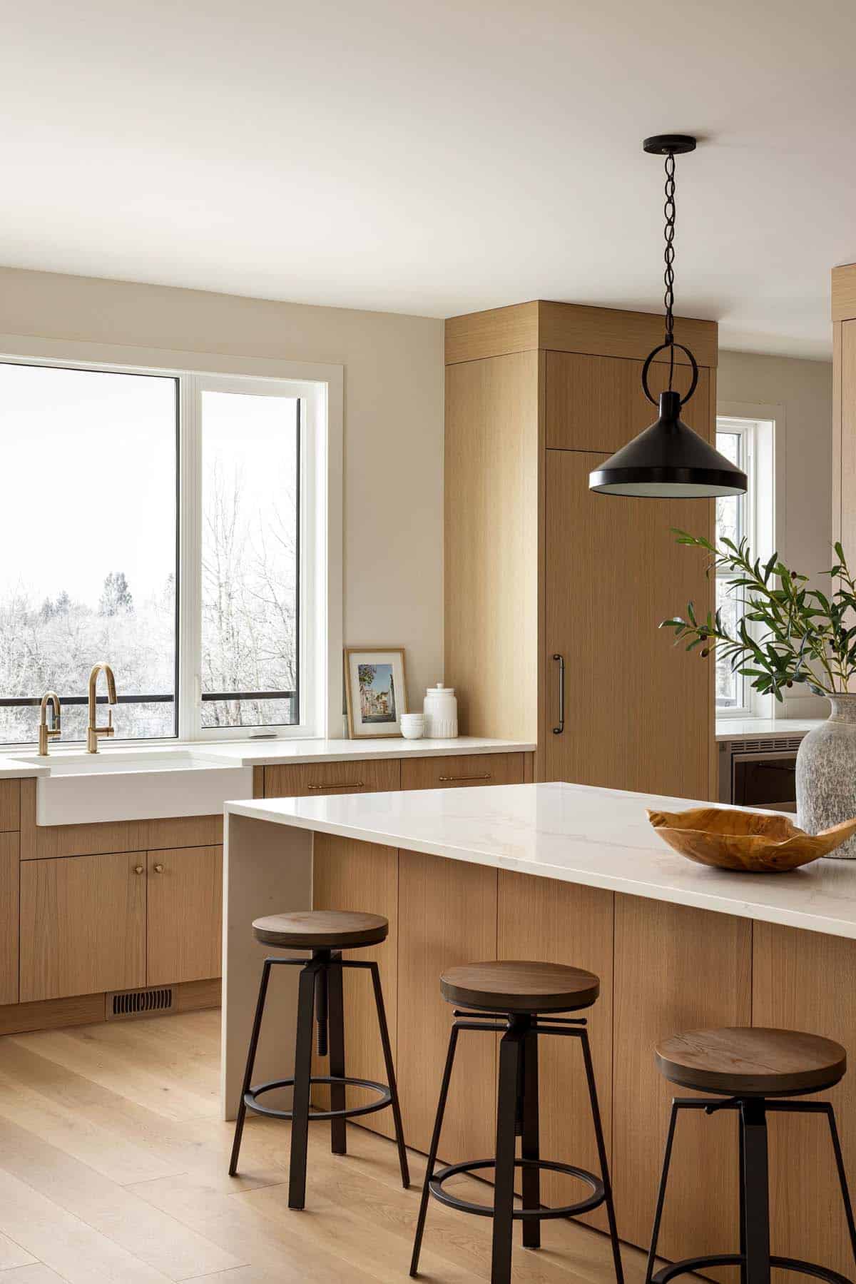 Kitchen island with brass fixtures and farmhouse sink by window