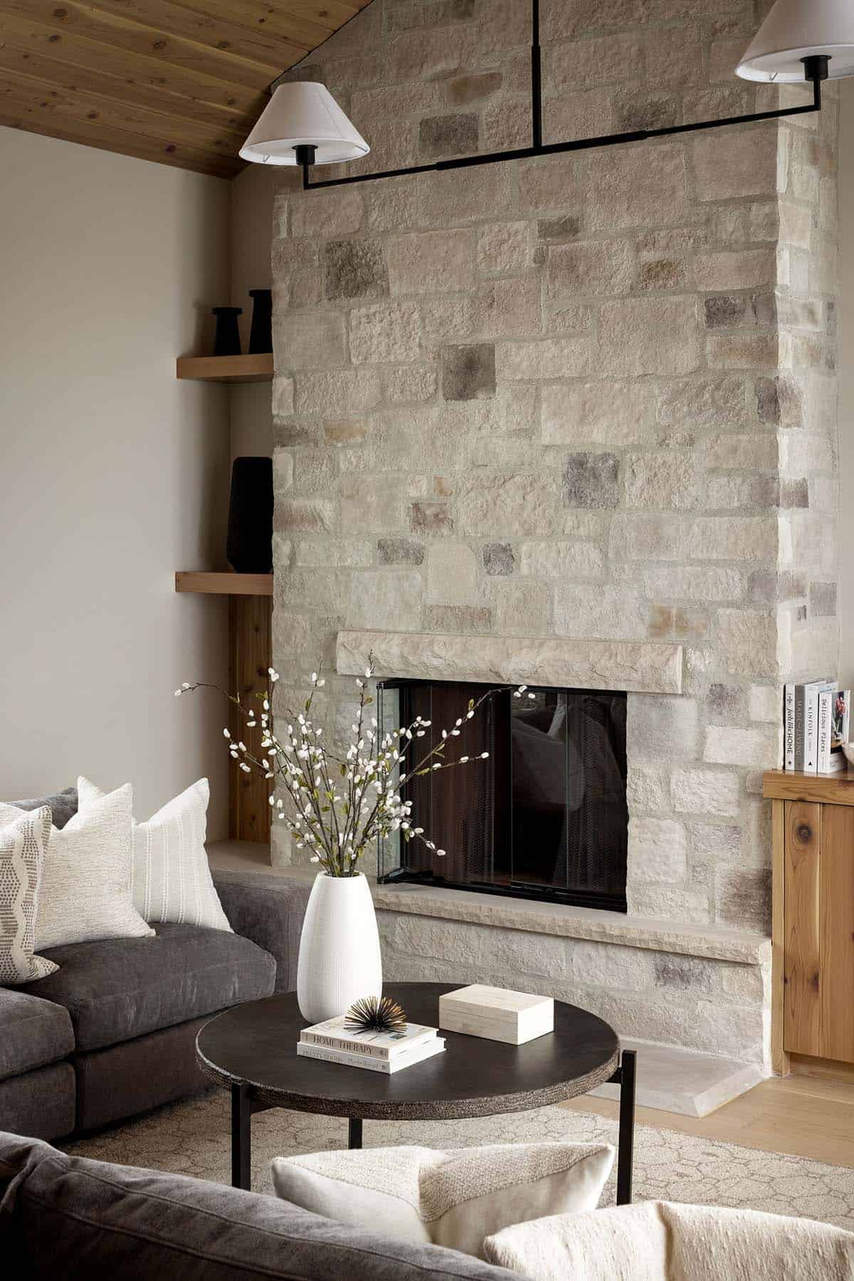 Stone fireplace detail with mantel and round black coffee table
