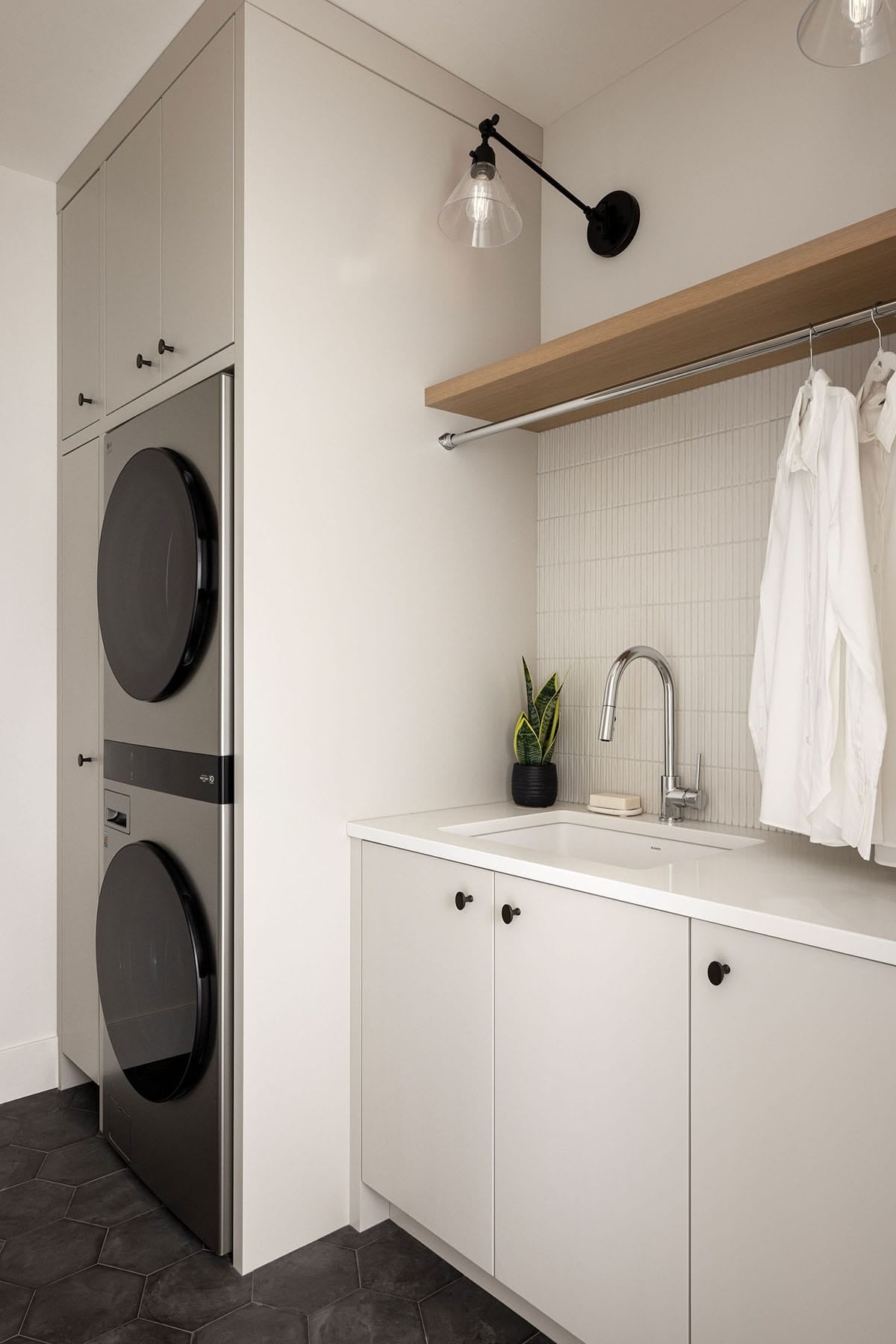 Laundry room with stacked washer dryer and hanging storage rod