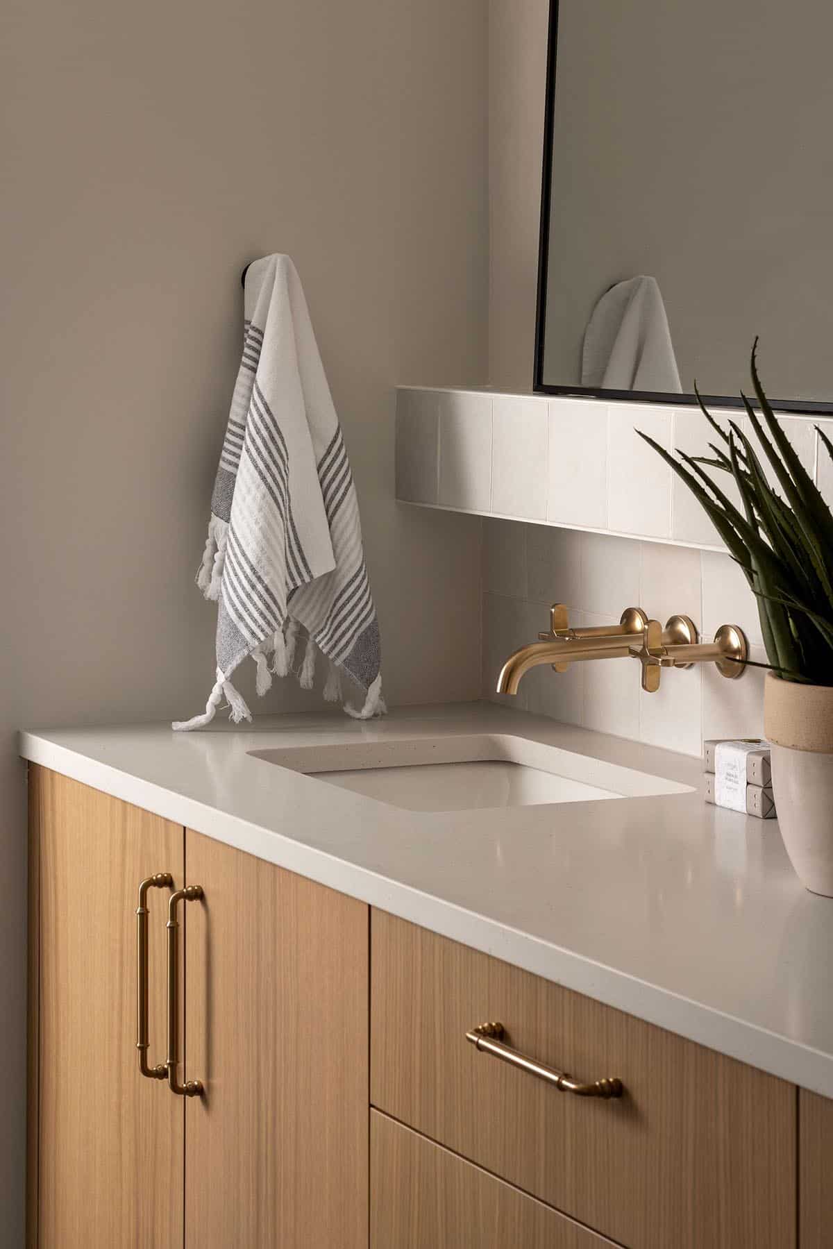 Bathroom vanity detail with brass fixtures and striped hand towel