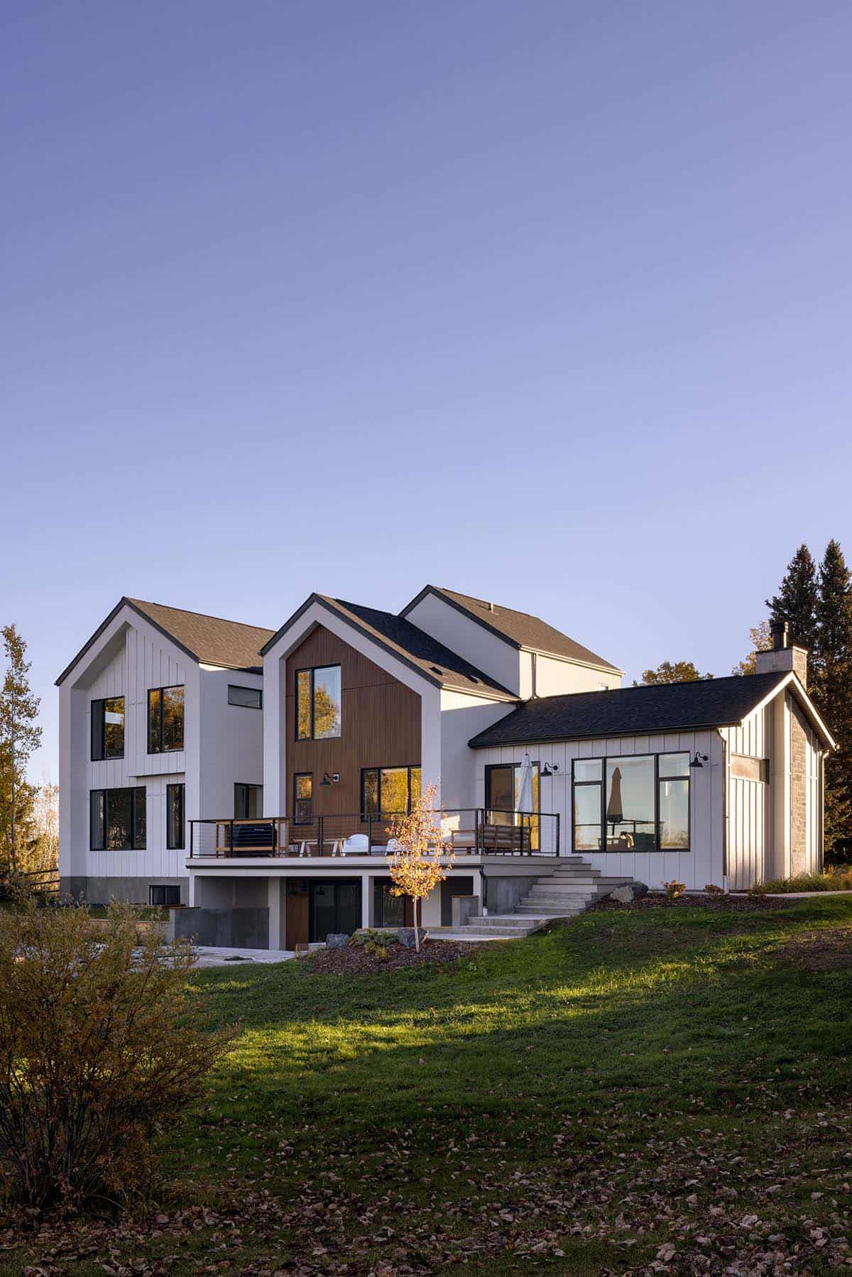 Rear exterior view of home with wraparound deck on hillside lawn