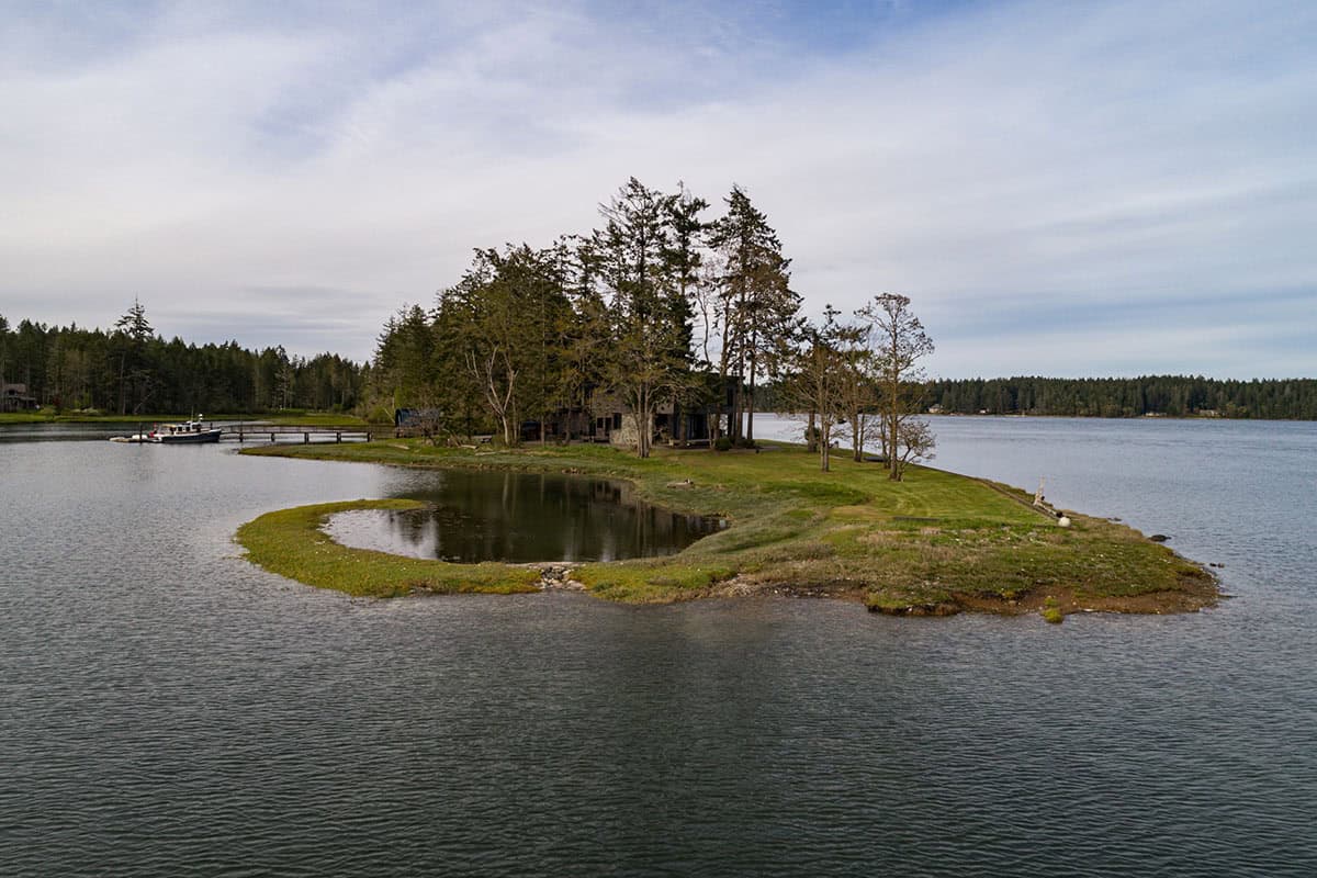Aerial view of the home nestled on a curved grassy point