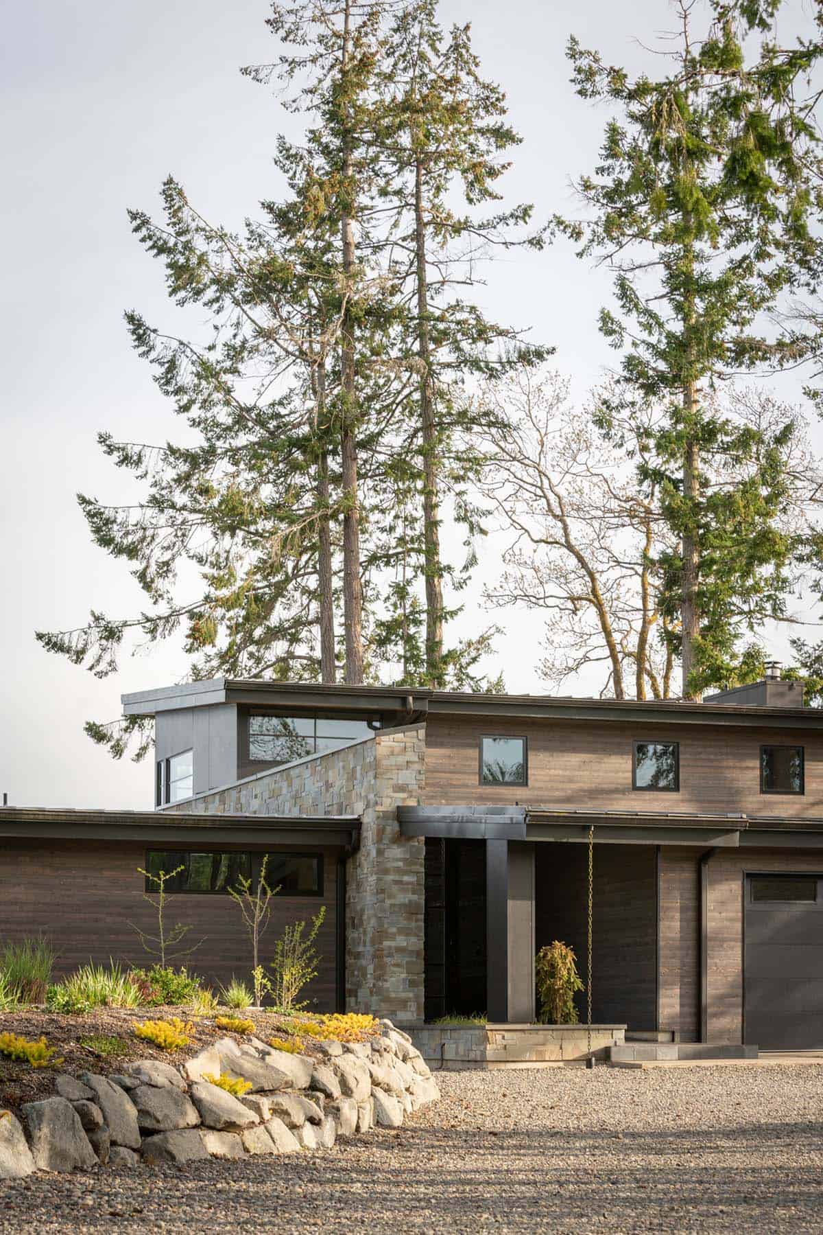 Front entrance with a stacked stone chimney and dark wood siding