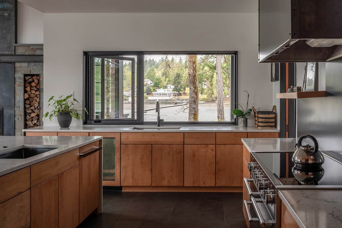 Kitchen sink window framing tree trunks and the bay beyond