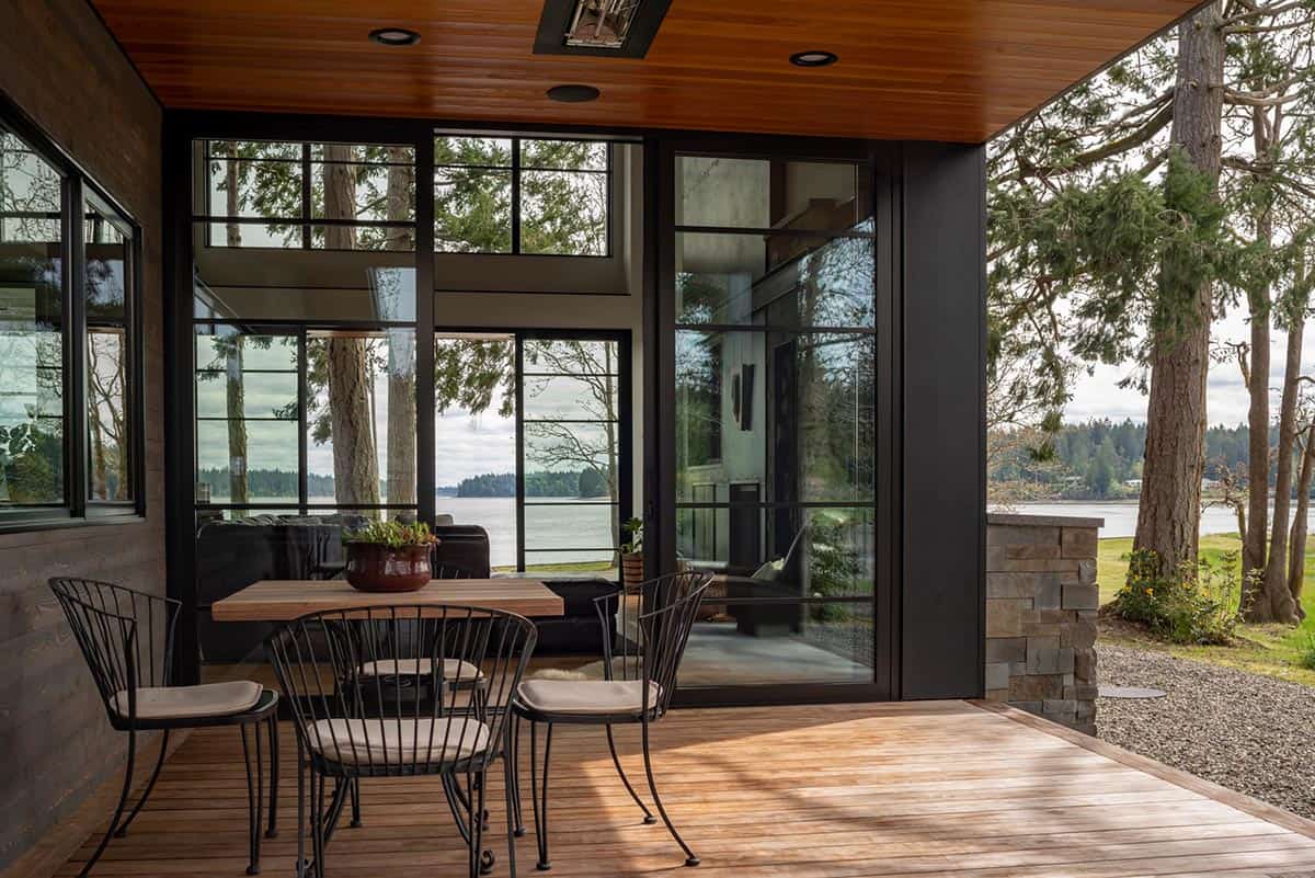 Covered patio dining area framed by black steel window walls