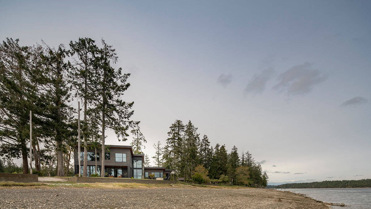 Dusk view of the home seen from the pebbled beach shoreline