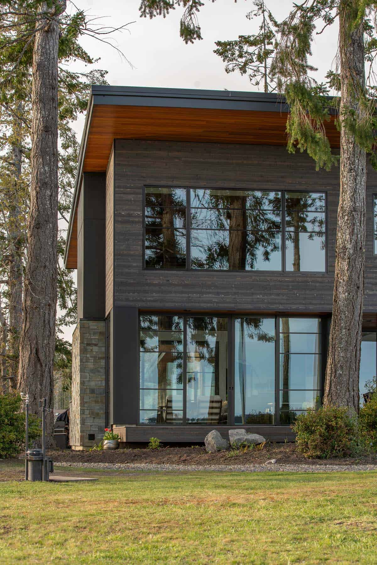 Two story facade with a stone base and dark wood cladding