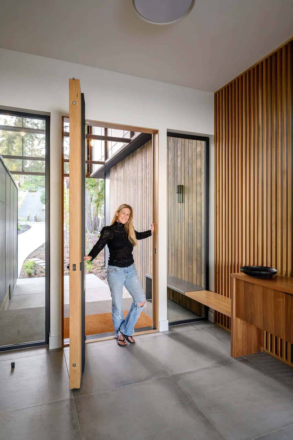Woman smiles beside open front door in entry foyer