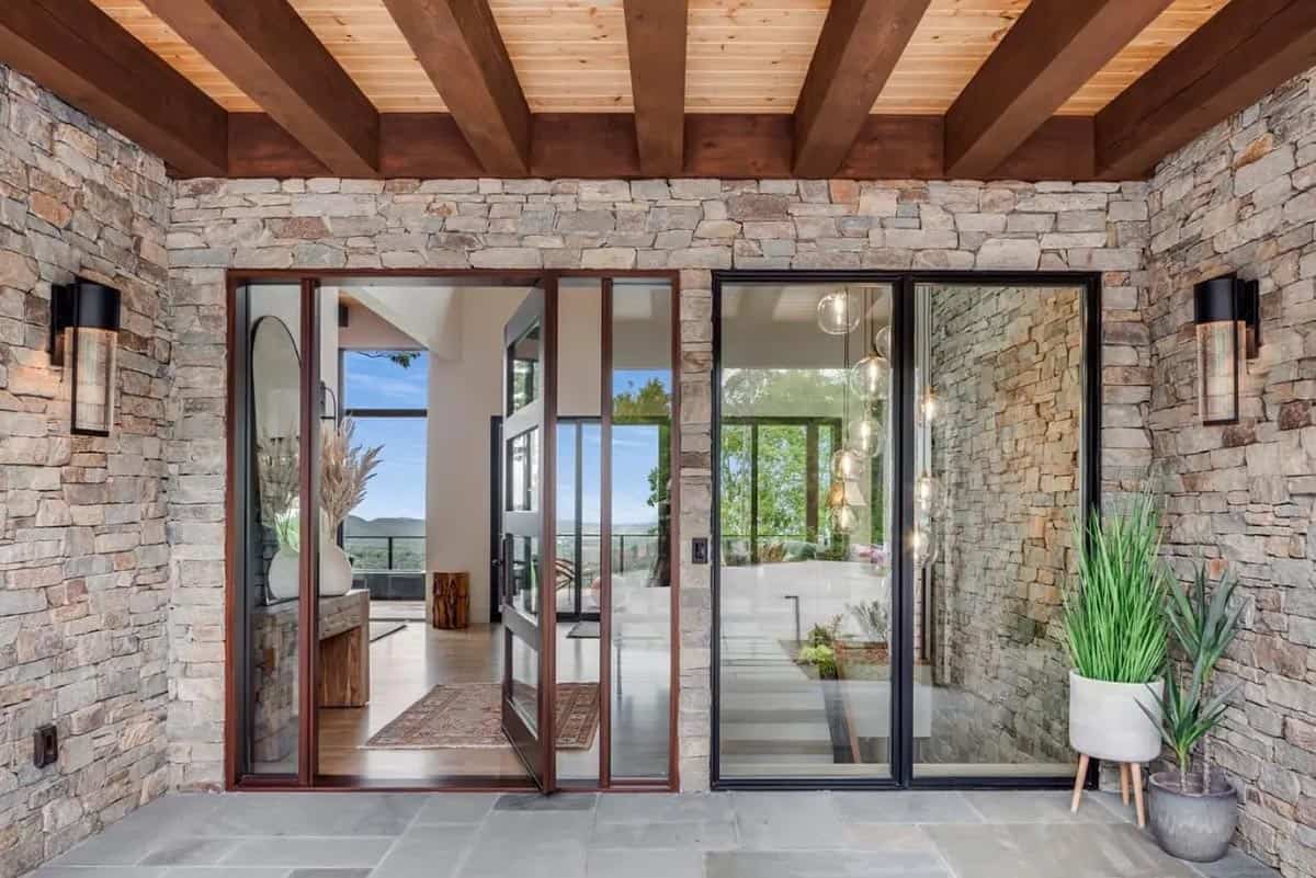 Covered entry with pivot door and mountain views through glass