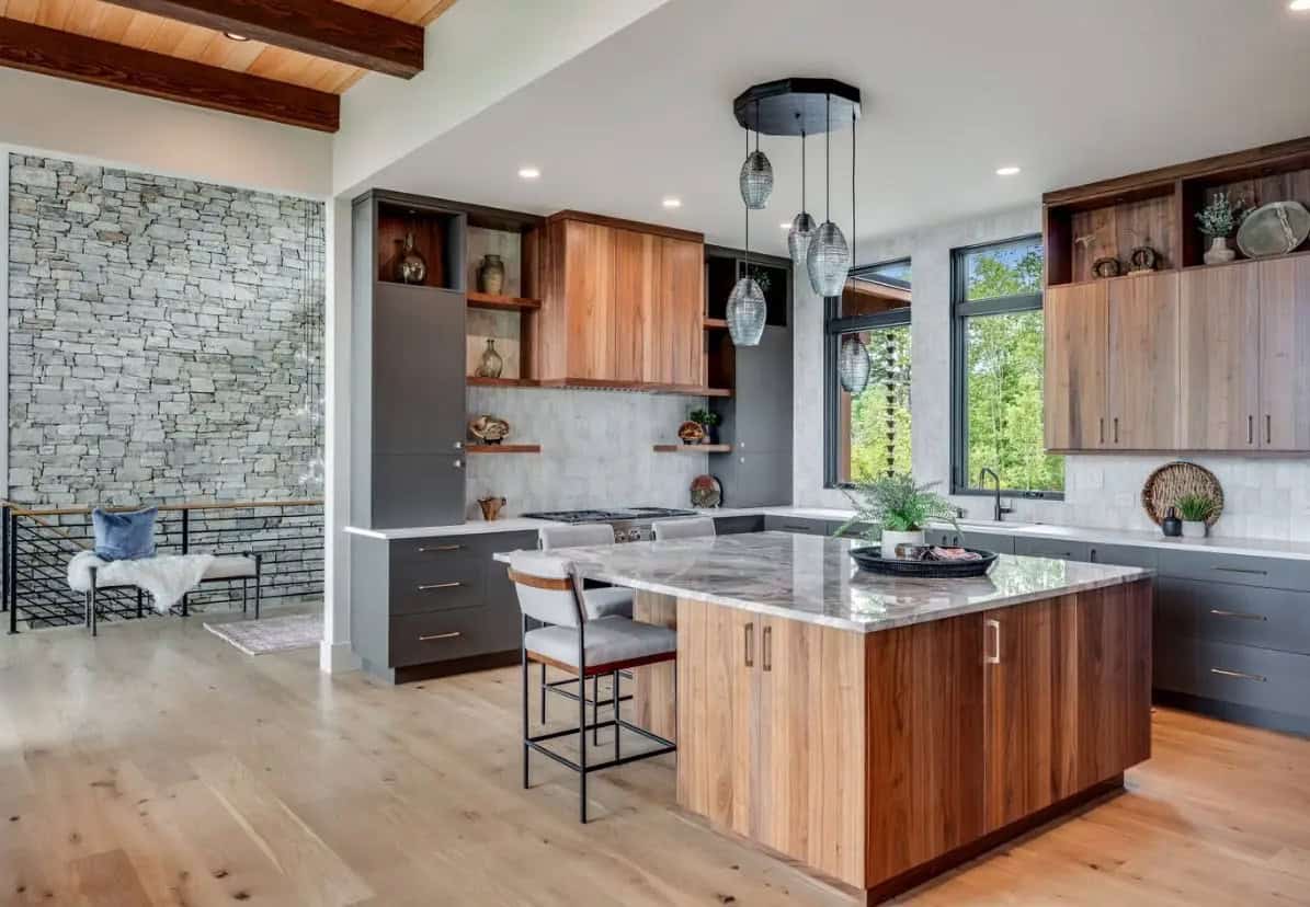 Kitchen island with marble countertop and walnut cabinetry against stone wall