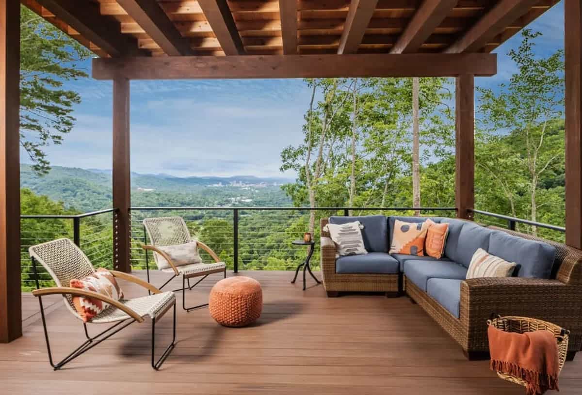 Covered deck with wicker sectional overlooking mountain and treetop views