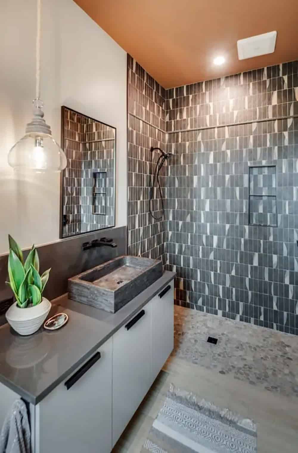 Bathroom shower with patterned tile walls and pebble stone flooring