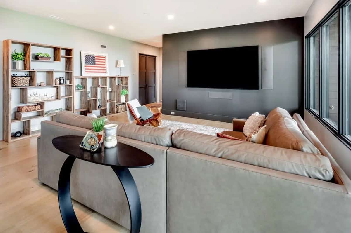 Media room with sectional sofa, dark accent wall, and mounted television