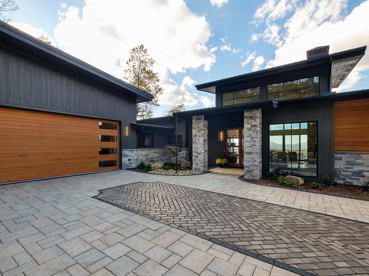Modern mountain home exterior with stone pillars and wood garage door