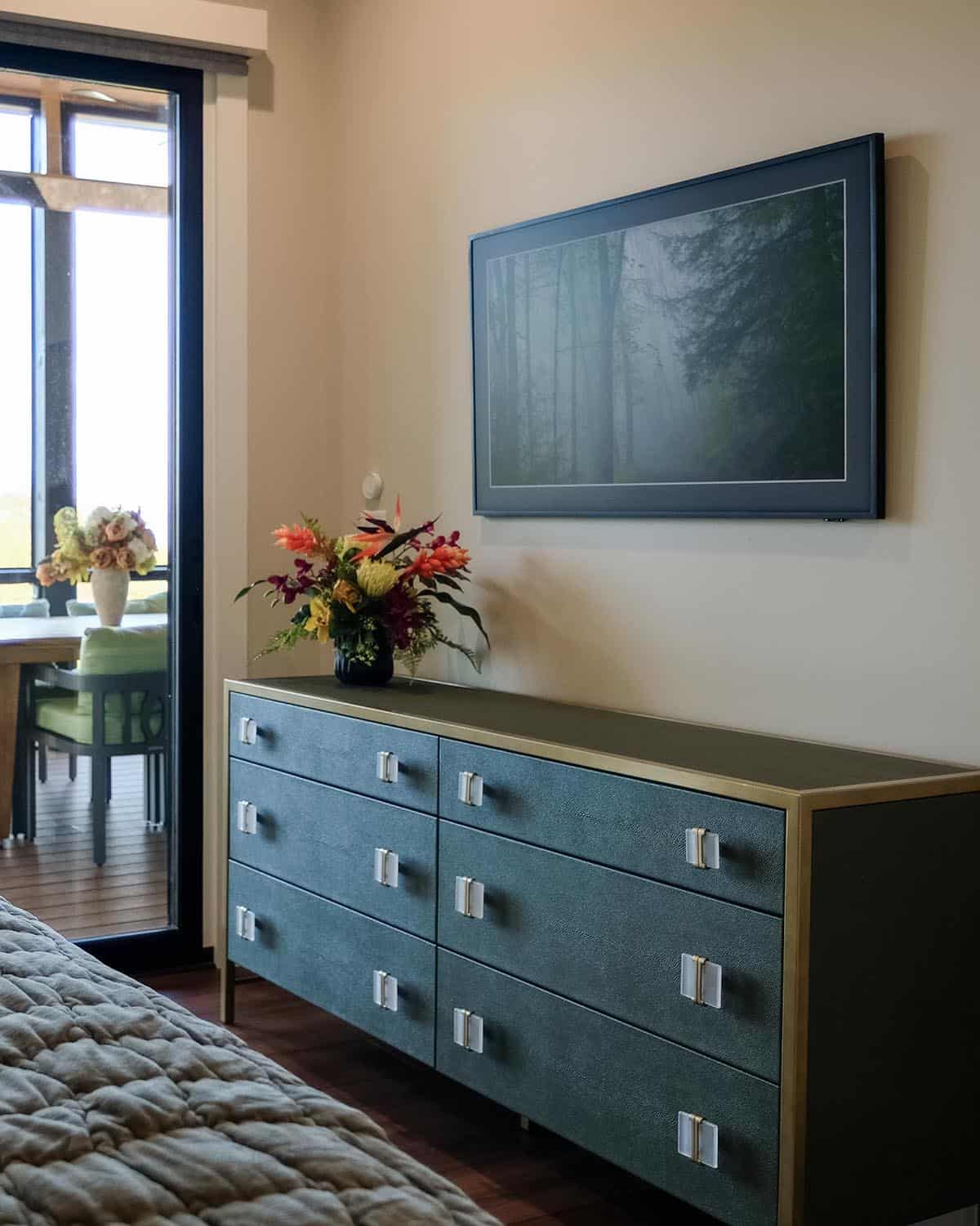 Bedroom dresser with framed art and fresh flower arrangement