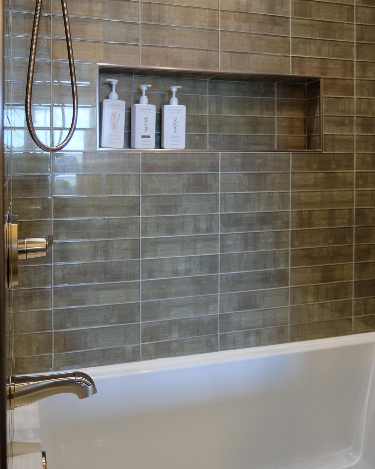 Green tile shower surround with built-in niche and toiletries