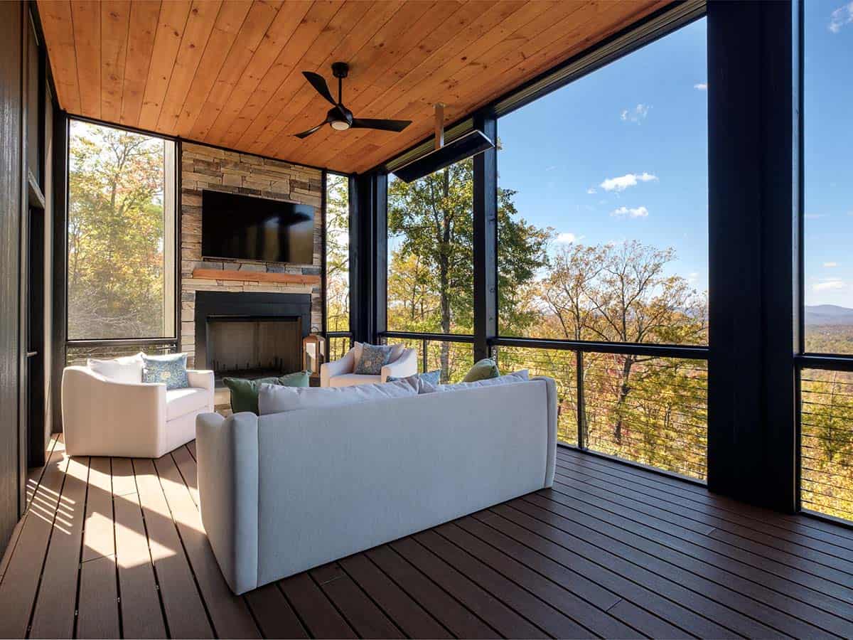 Screened porch seating with stacked stone fireplace and mounted TV