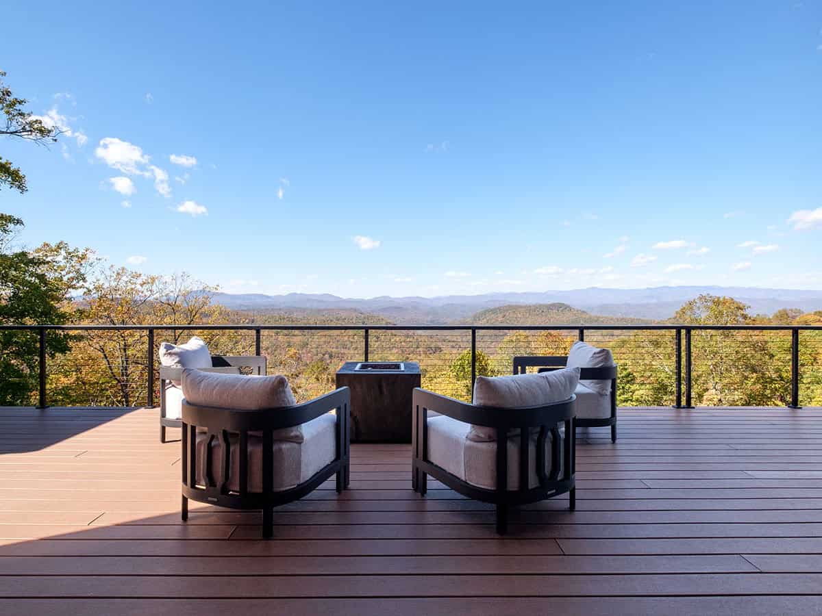 Deck lounge chairs and fire table facing mountain horizon