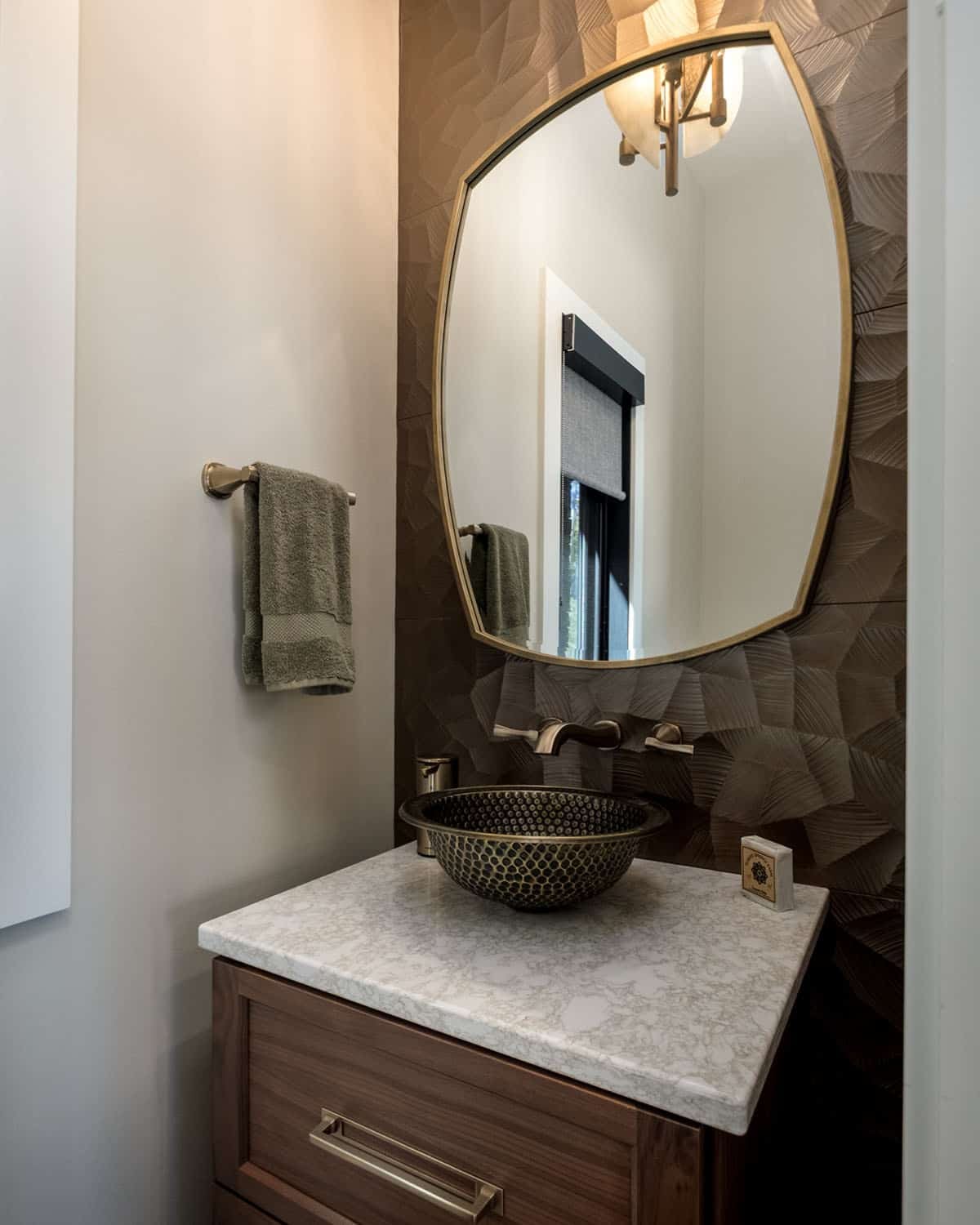 Powder room with hammered brass vessel sink and arched mirror