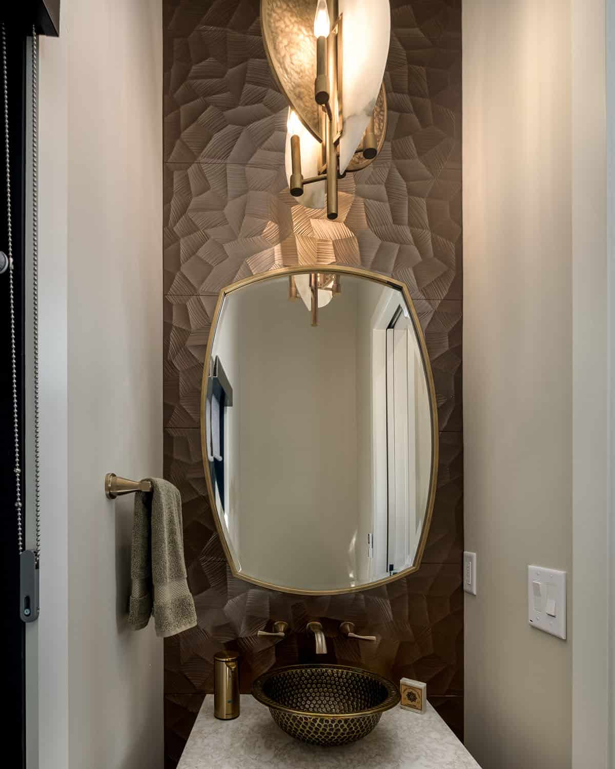 Powder room vanity with sculptural sconce and textured tile wall