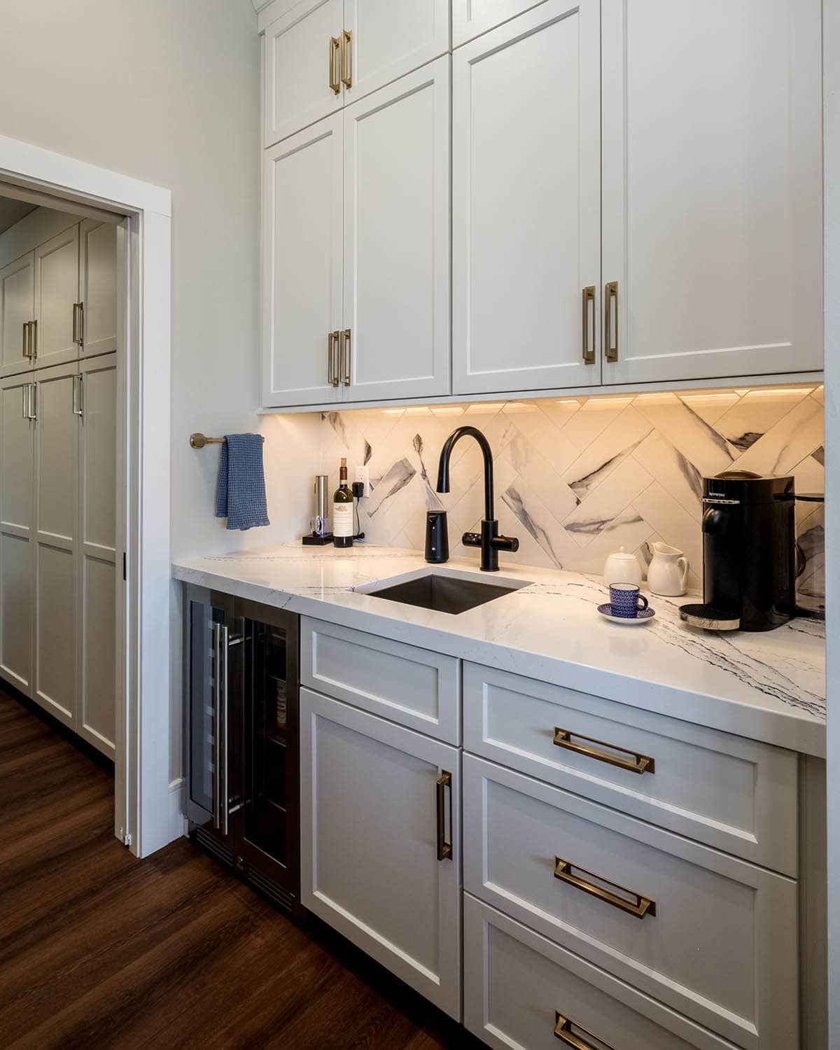 Butler's pantry with marble herringbone backsplash and wine fridge