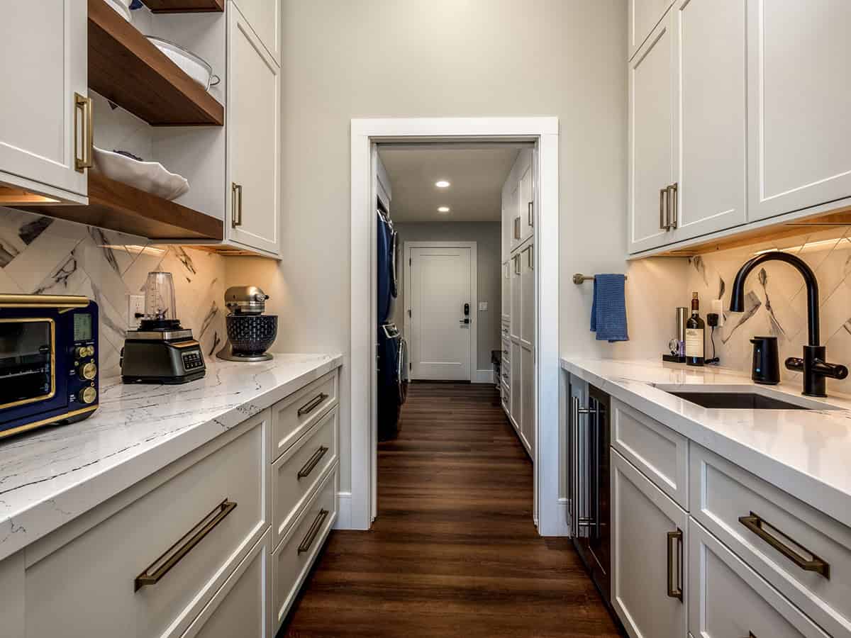 Butler's pantry hallway with marble backsplash and floating shelves