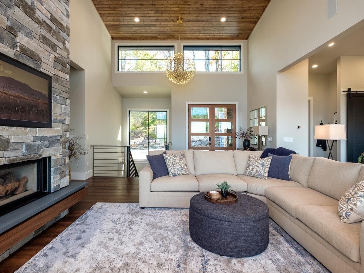 Living room sectional with stacked stone fireplace and vaulted ceiling