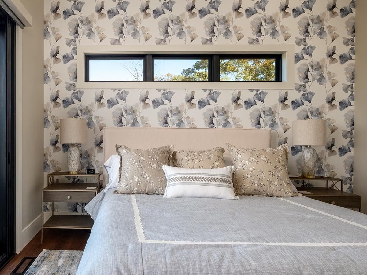 Guest bedroom with floral wallpaper and upholstered headboard