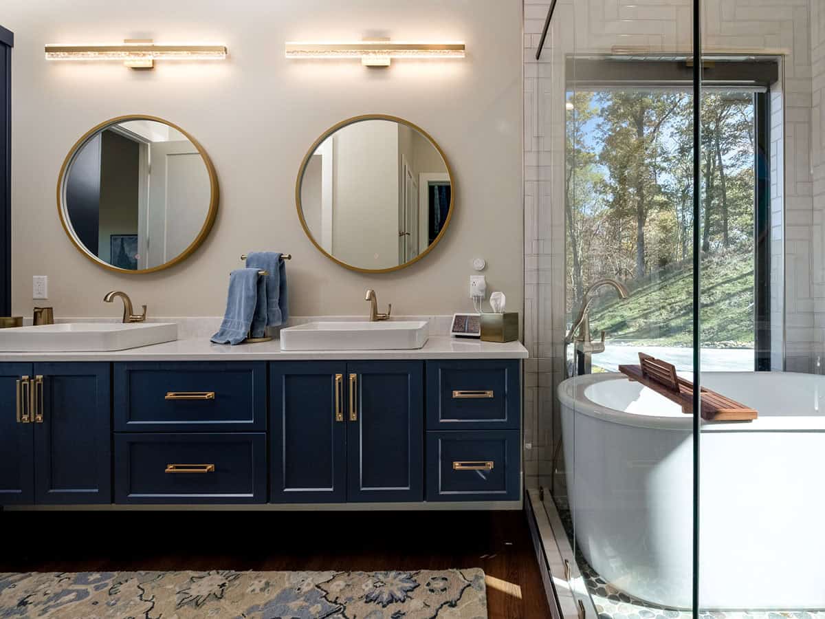 Primary bathroom vanity with navy cabinetry and soaking tub